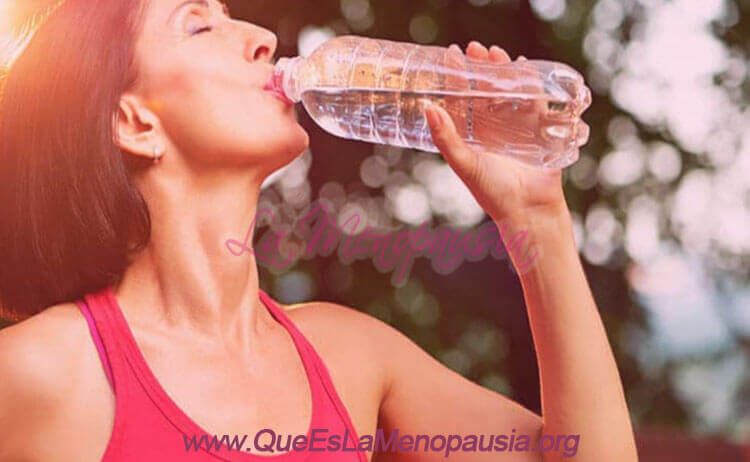 Mujer tomando agua para aliviar un sofoco